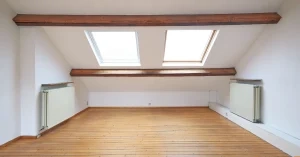 Bright attic room with two skylights set in a sloped ceiling above wood floors