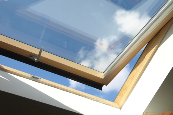 Sun streaming in open venting skylight with a wood frame showing blue sky and clouds